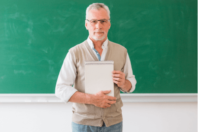 seniormaleprofessorholdingnotebookstandingagainstblackboard1_i4mtc_390