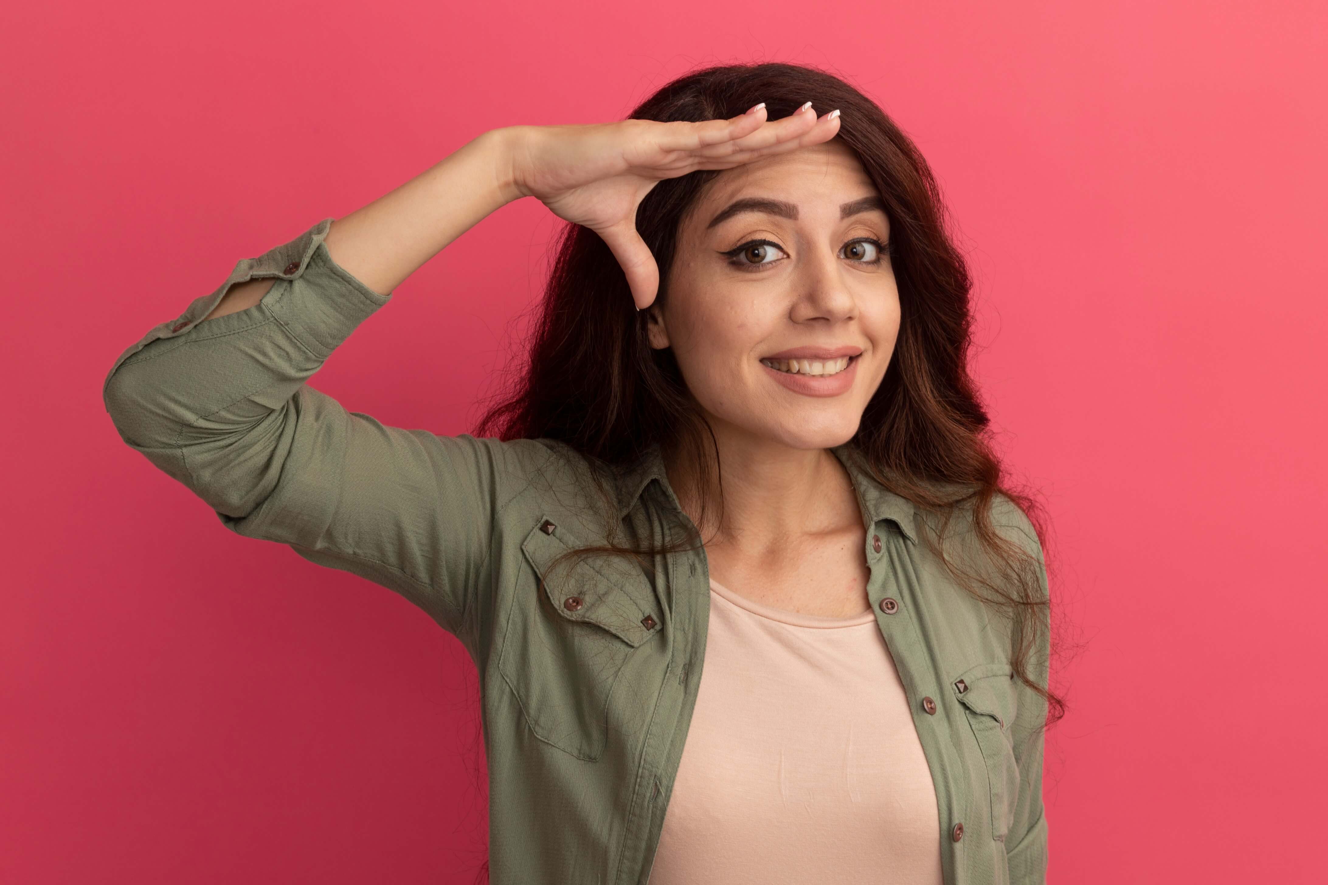smilingyoungbeautifulgirlwearingolivegreentshirtshowingsalutegestureisolatedpinkwall1_1v51q_4368